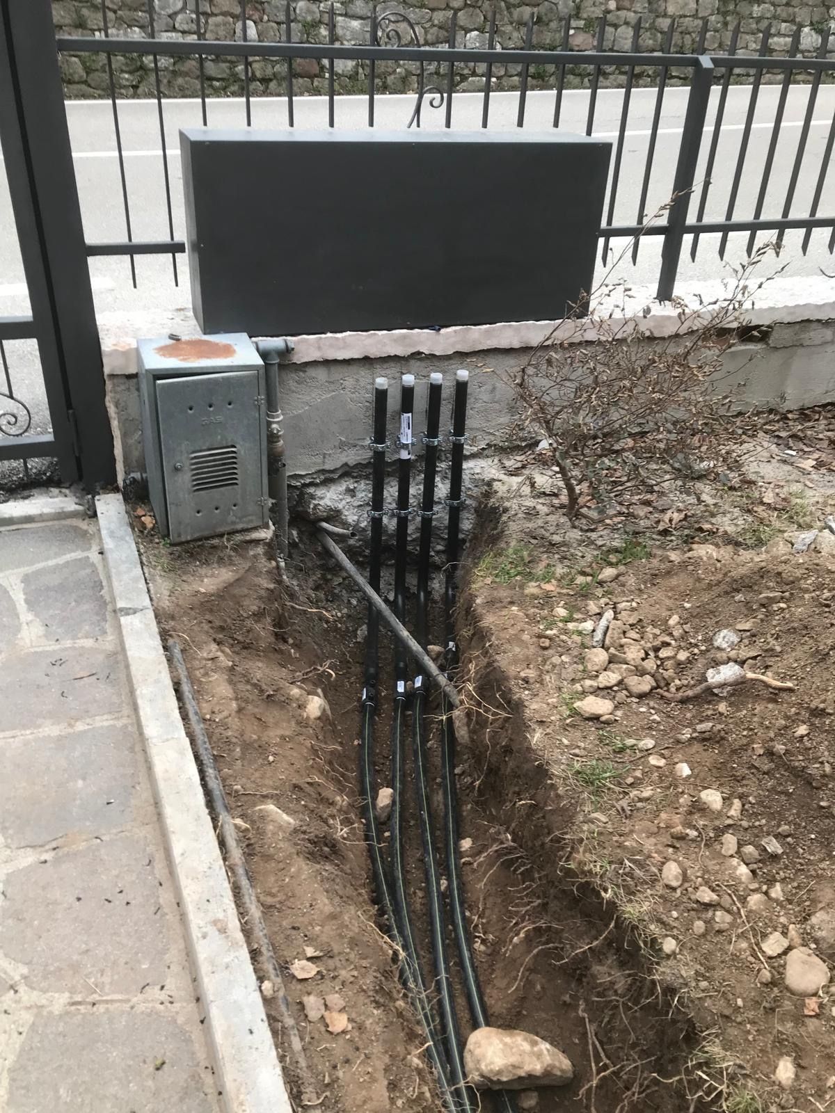 Scavo aperto lungo la recinzione con quattro tubazioni gas in polietilene nero posate sul fondo e risalite verso l'armadio dei contatori